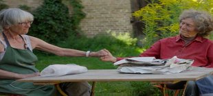 Akteurinnen am Tisch mit gereichten Händen