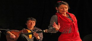Im Vordergrund eine tanzende Frau in Hintergrund ein Mann mit Gitarre