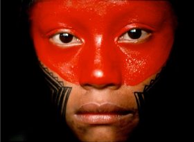 Nahe Portraitaufnahme einer amazonischen Einwohnerin mit auffälliger roter und schwarzer Gesichtsbemalung.