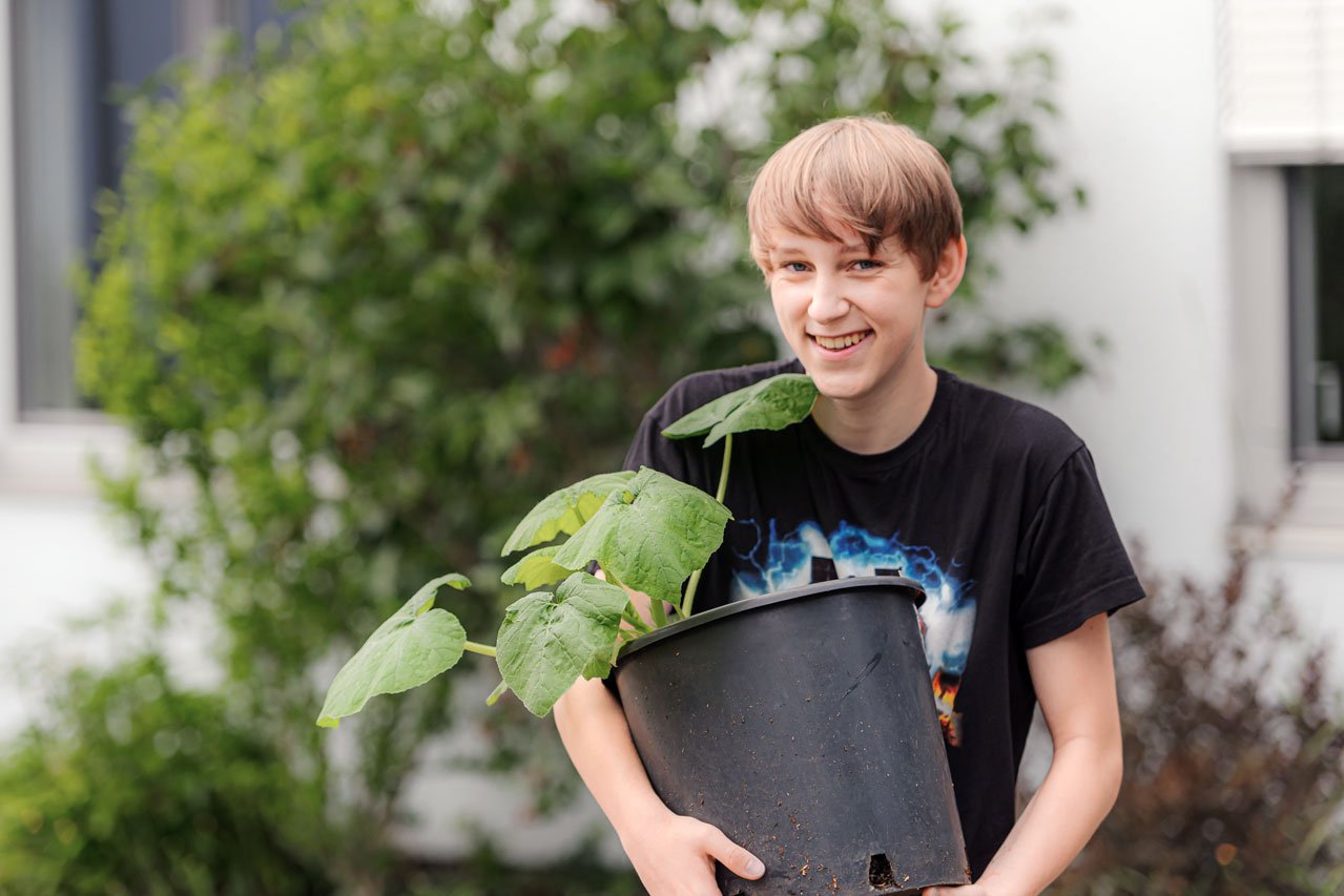 Eine Jugendlicher mit einem Pflanzentopf
