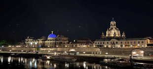 Beleuchtete Silhouette der Stadt Dresden bei Nacht mit dem Fluss Elbe im Vordergrund