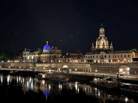 Beleuchtete Silhouette der Stadt Dresden bei Nacht mit dem Fluss Elbe im Vordergrund