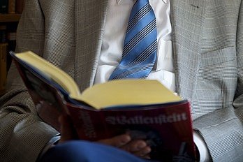 Ein älterer Mann hält ein aufgeschlagenes Buch in den Händen