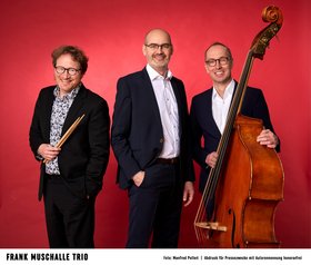 Die Musiker des Frank Muschalle Trio vor rotem Hintergrund