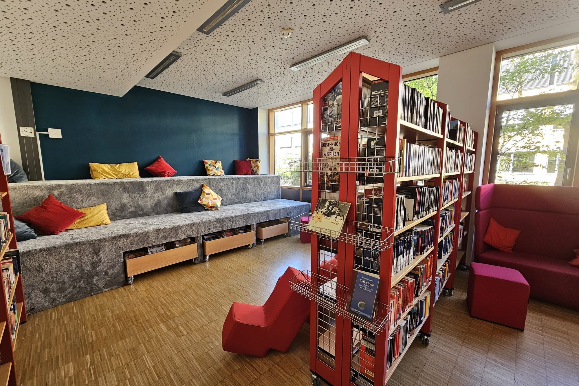 Ein volles Bücherregal und gemütliche Sitzmöglichkeiten in der Schulbibliothek der Samuel-Heinicke-Realschule 