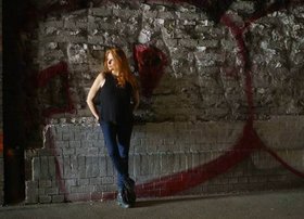 schauspielerin an Felswand lehnend