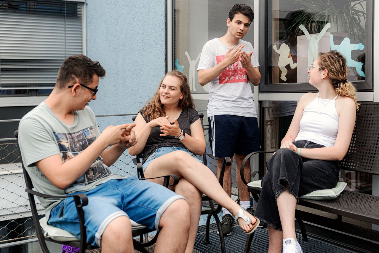 Eine Gruppe von Freunden unterhält sich in Gebärdensprache auf der Terrasse des Augustinum Studienheims