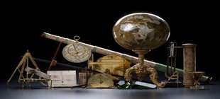 Prunkvolles Fernrohr, Landkarten, Weltkugel und ein Sextant vor einem schwarzen Hintergrund