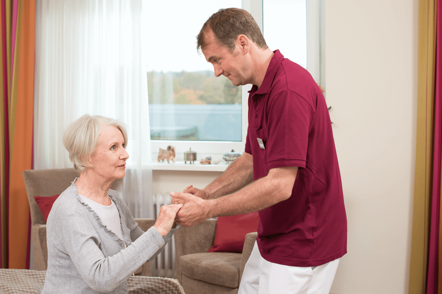 Pfleger hilft älterer Dame beim Aufstehen