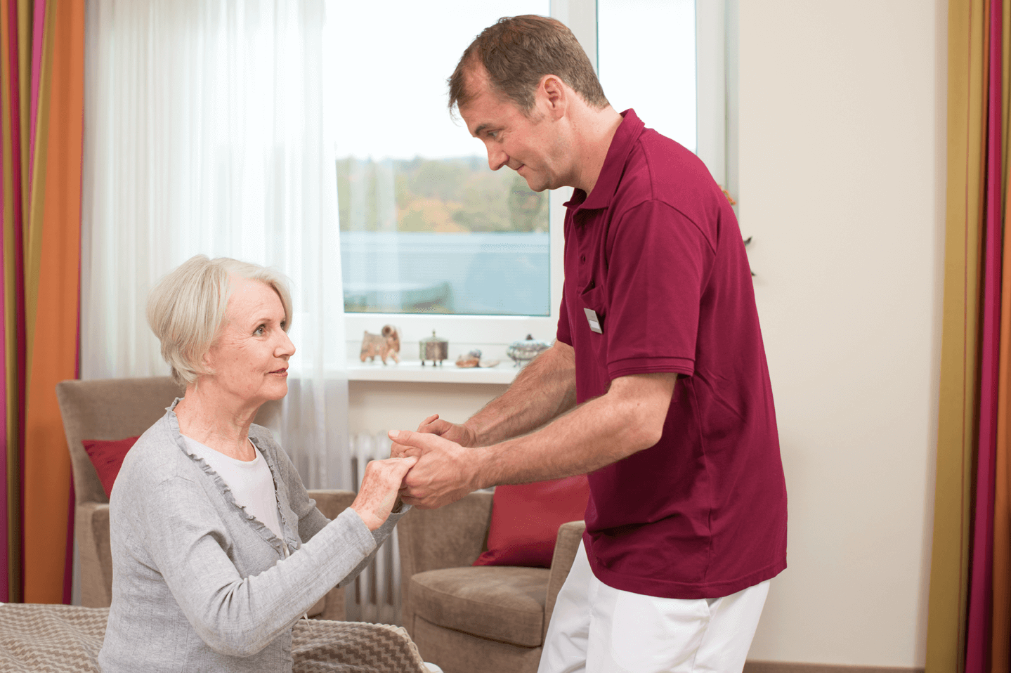 Pfleger hilft älterer Dame beim Aufstehen