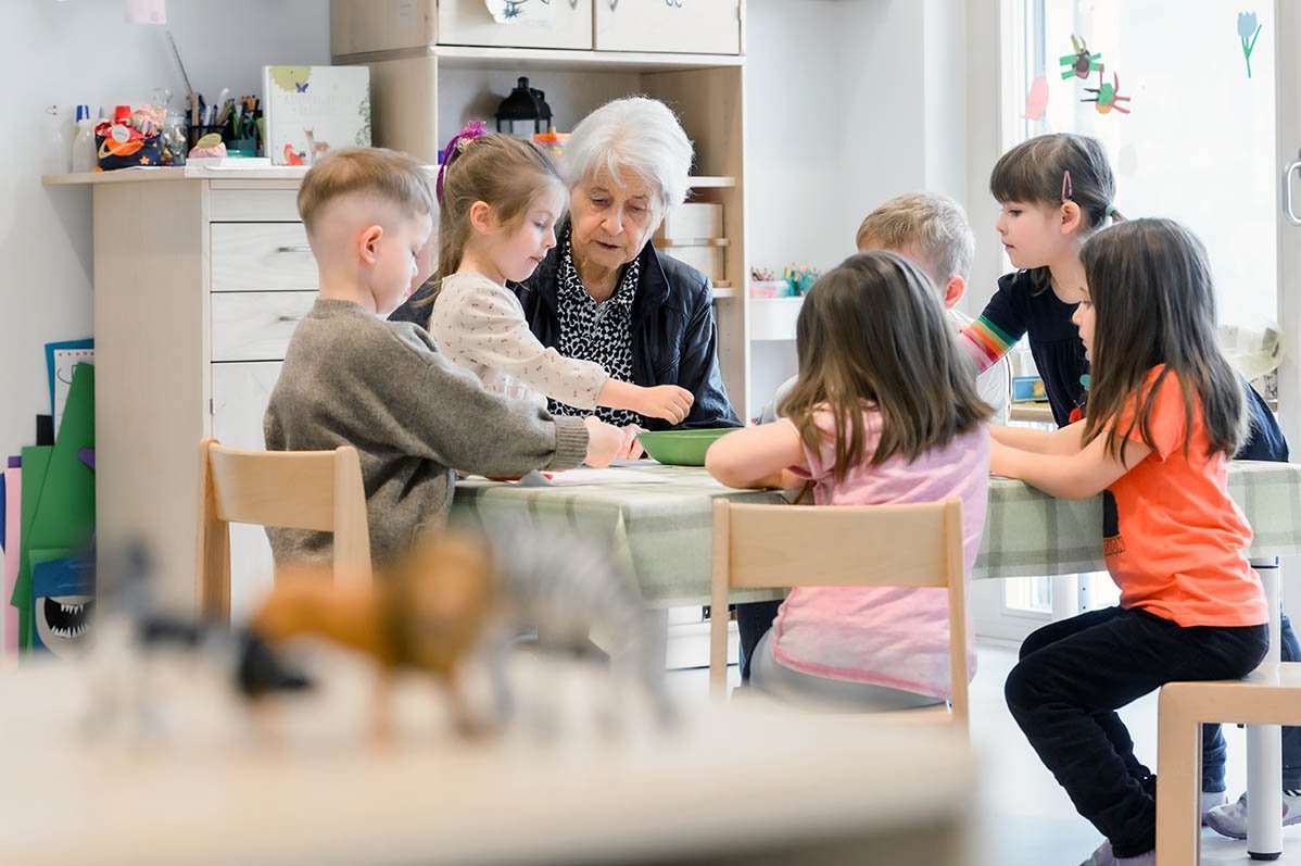 Lissy Benkler umringt von Kindergartenkindern an einem Tisch