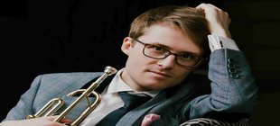 Junger Mann mit Brille, Anzug und Krawatte mit einer Trompete in der Hand