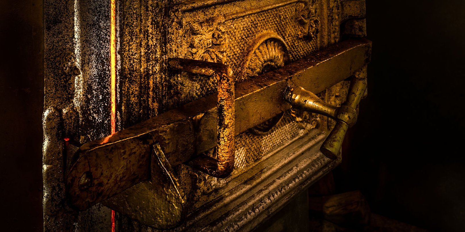 geschlossene Tür eines alten Ofens, durch die das Feuer hindurchschimmert