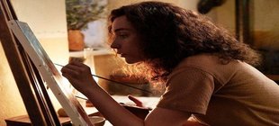 Eine Frau zeichnet mit Pinsel auf einer Leinwand